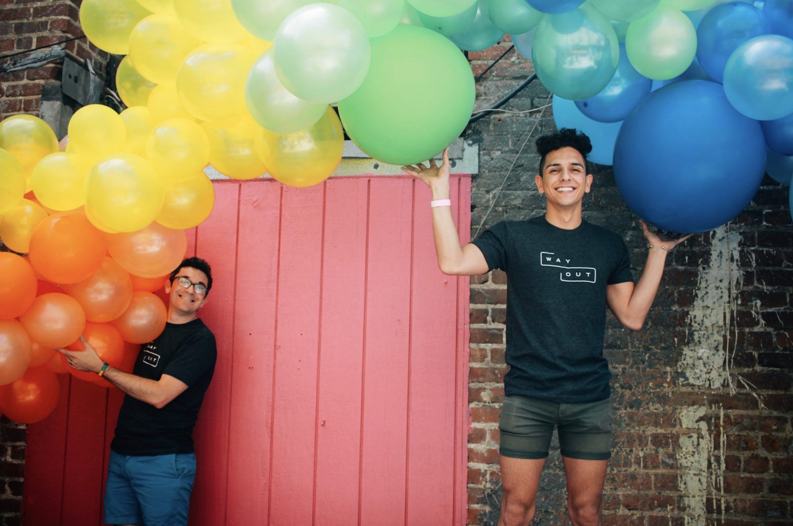 A volunteer under a rainbow balloon arch