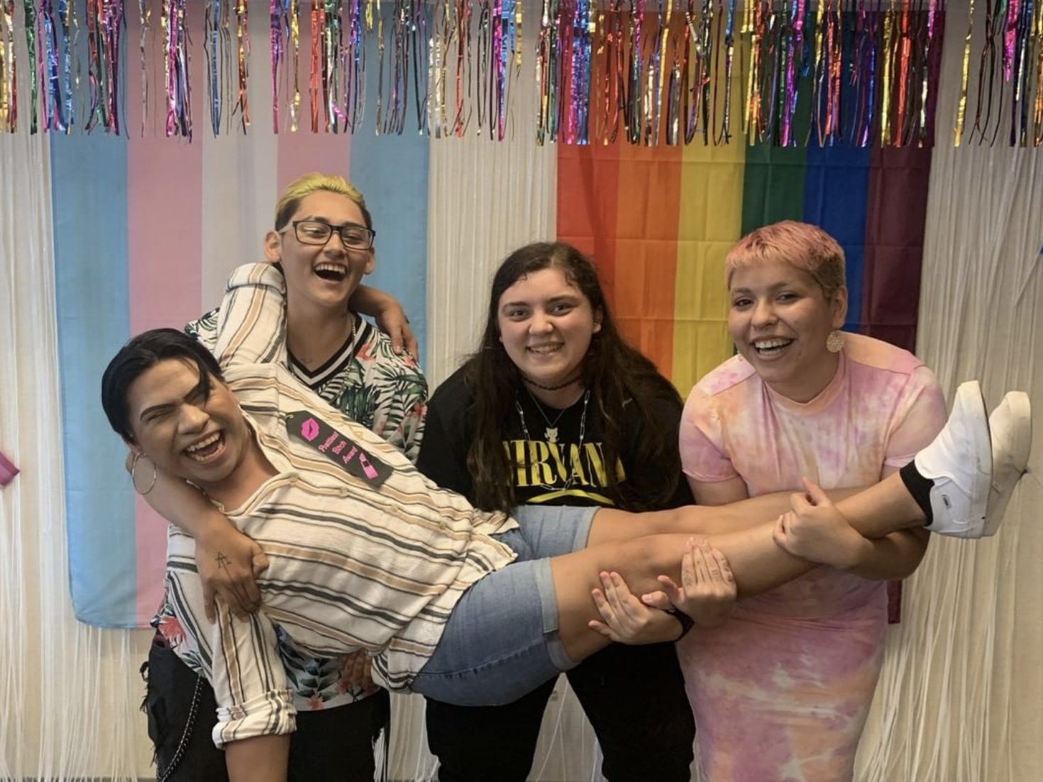 Friends pose under a rainbow streamer wall